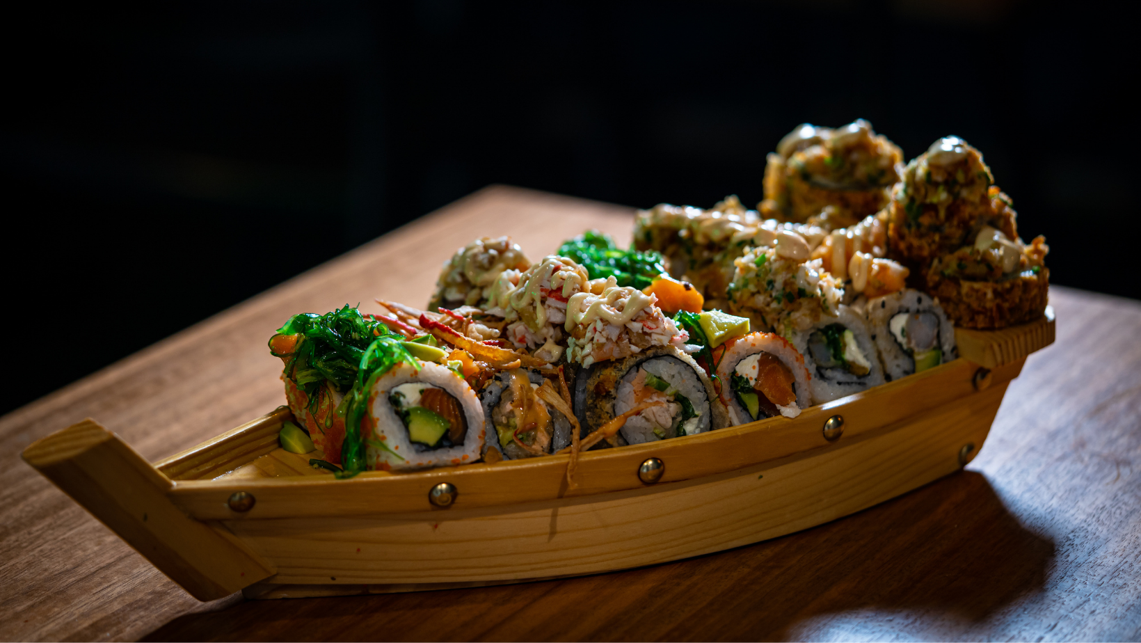 Varias piezas de sushi presentadas en un barco de madera.